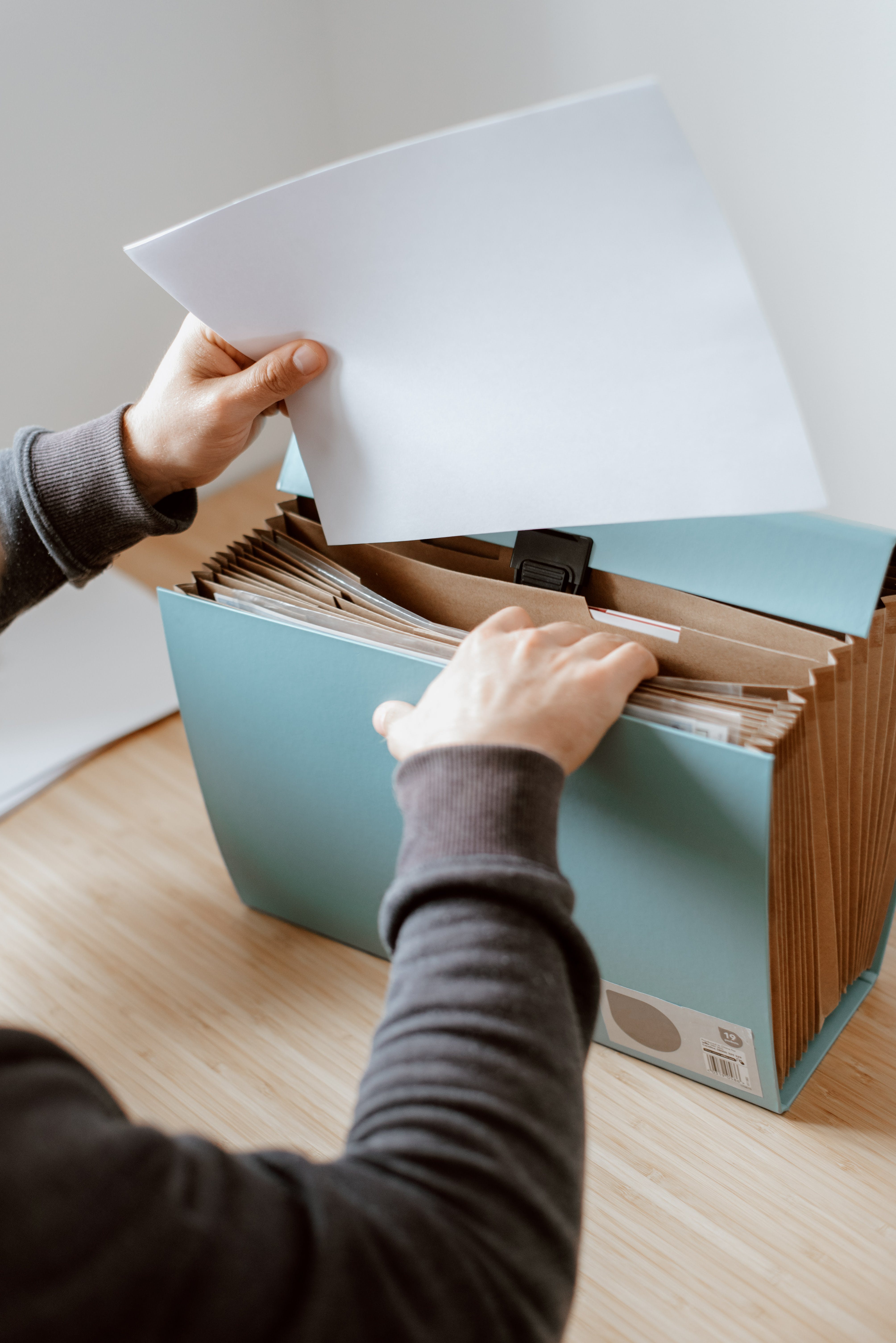 A person inserting a file into a folder among a group of folders.